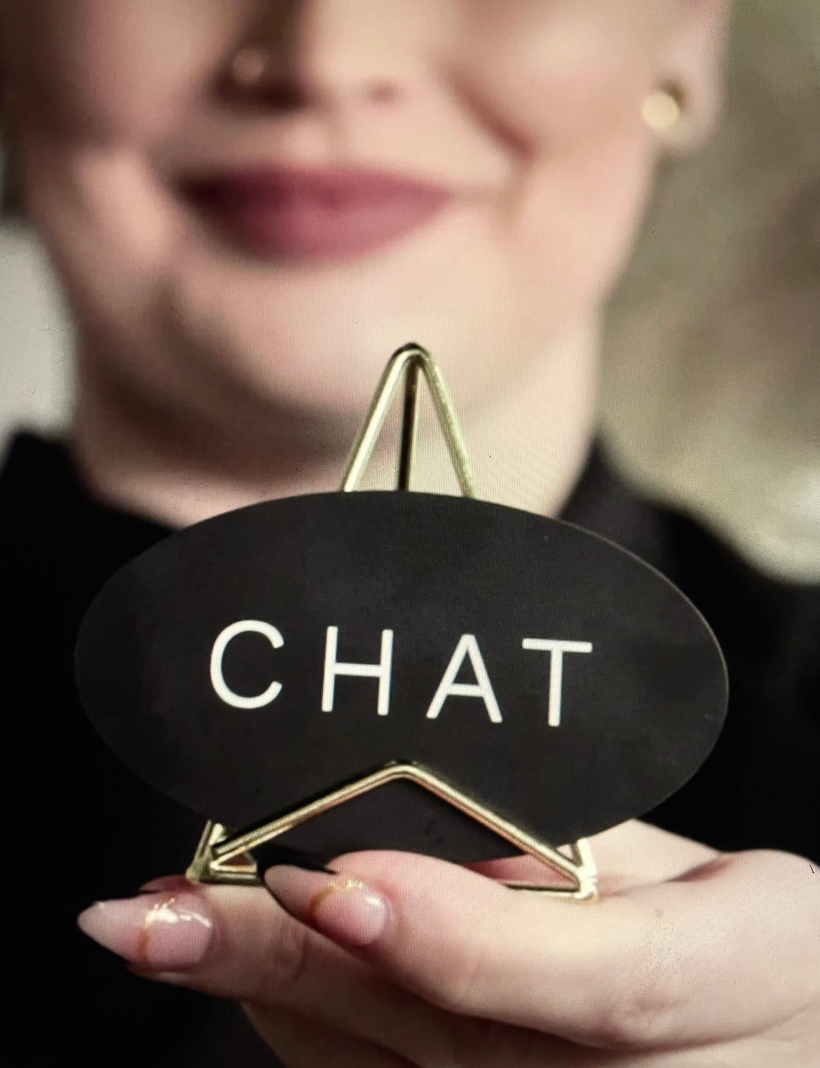 Person in black clothing, describing and holding a device used at a salon to express "chat" or "chill"